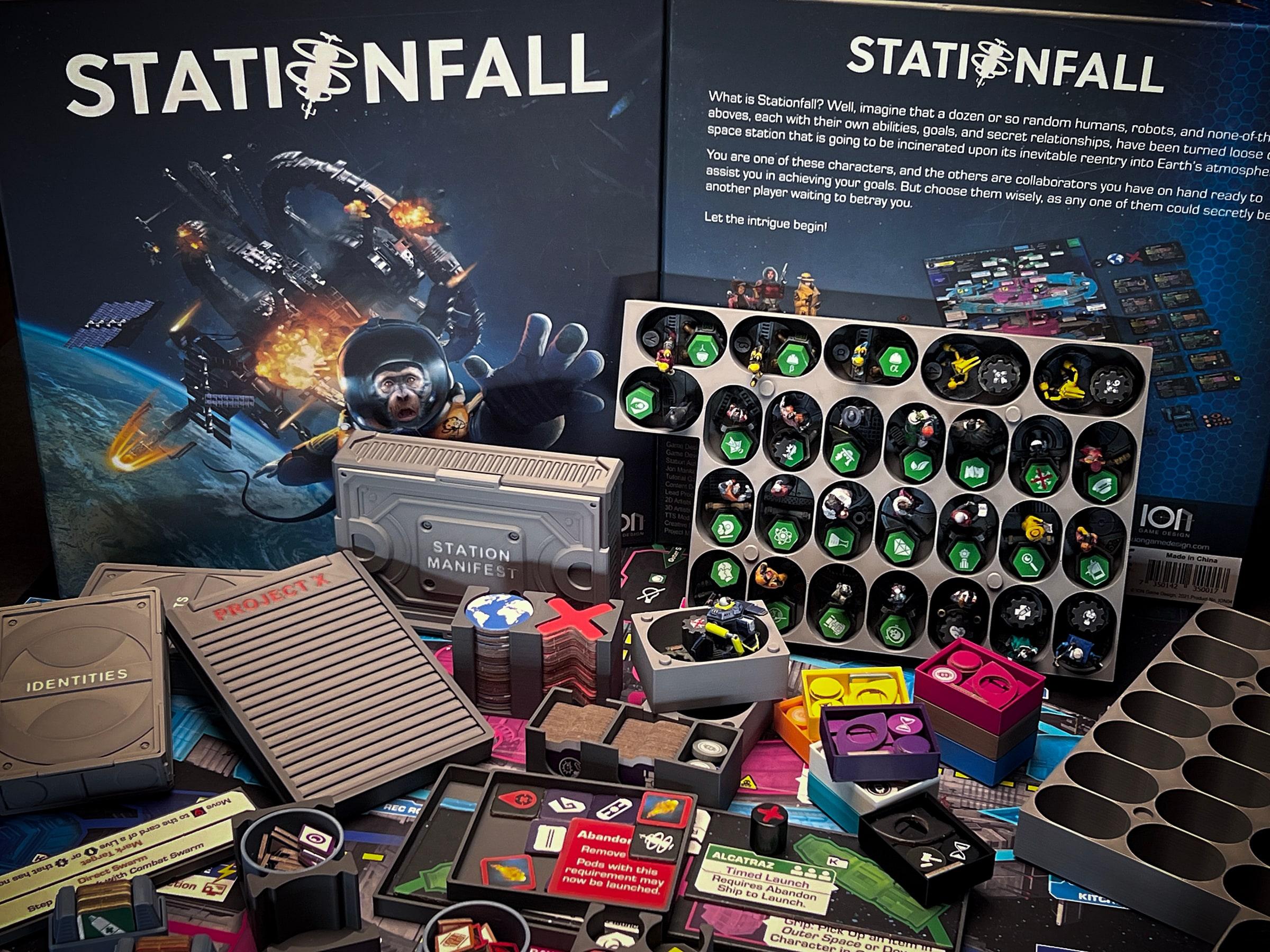 The Stationfall insert with its trays full of the game's tokens and cards, in front of the game box.