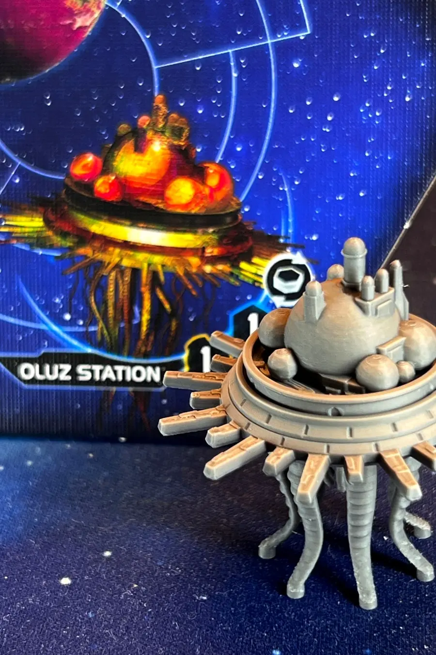 A printed Oluz space-station miniature for Twilight Imperium, standing on its system tile.